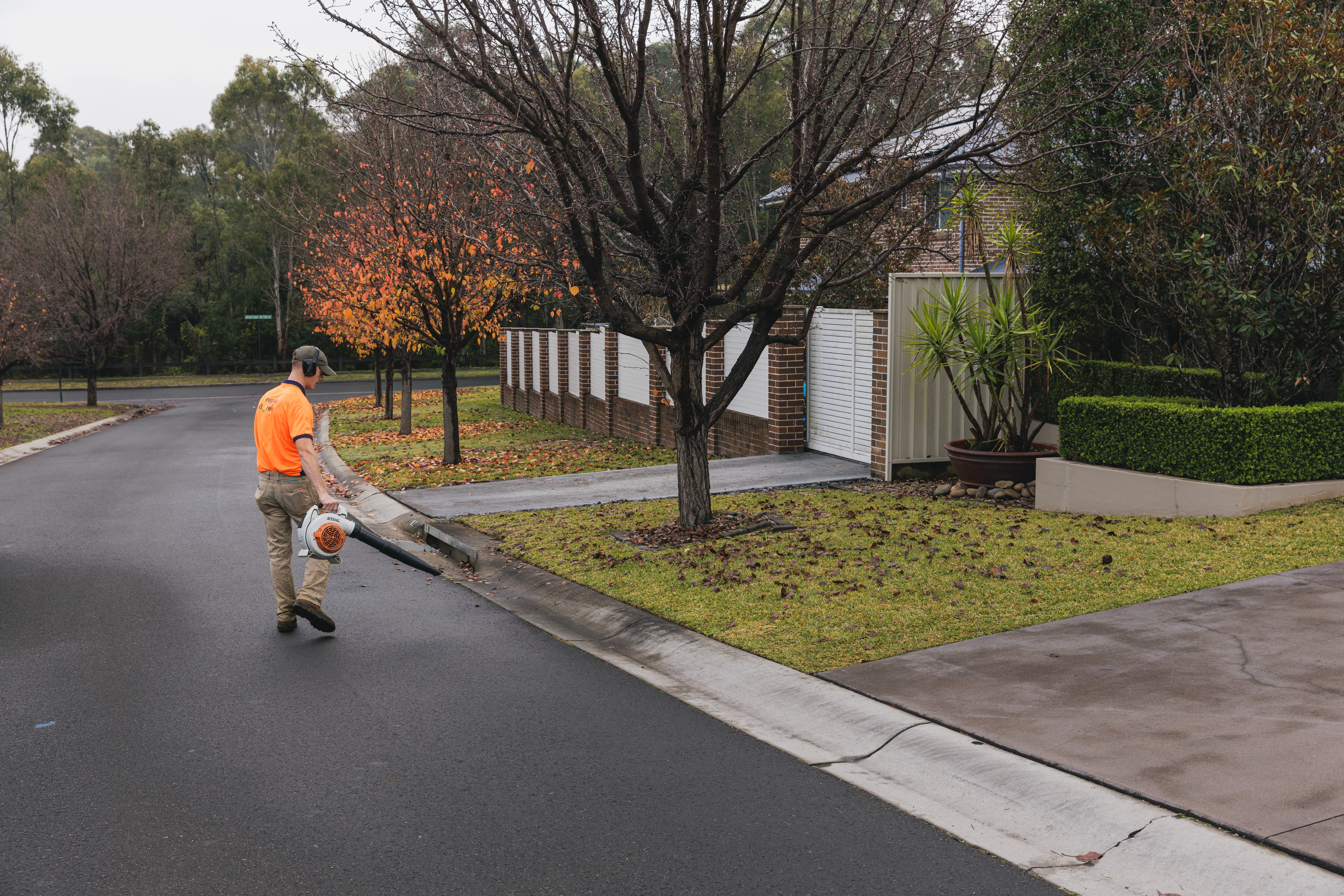 Keeping It Green team member using a blower to clear autumn leaves from a Camden street gutter