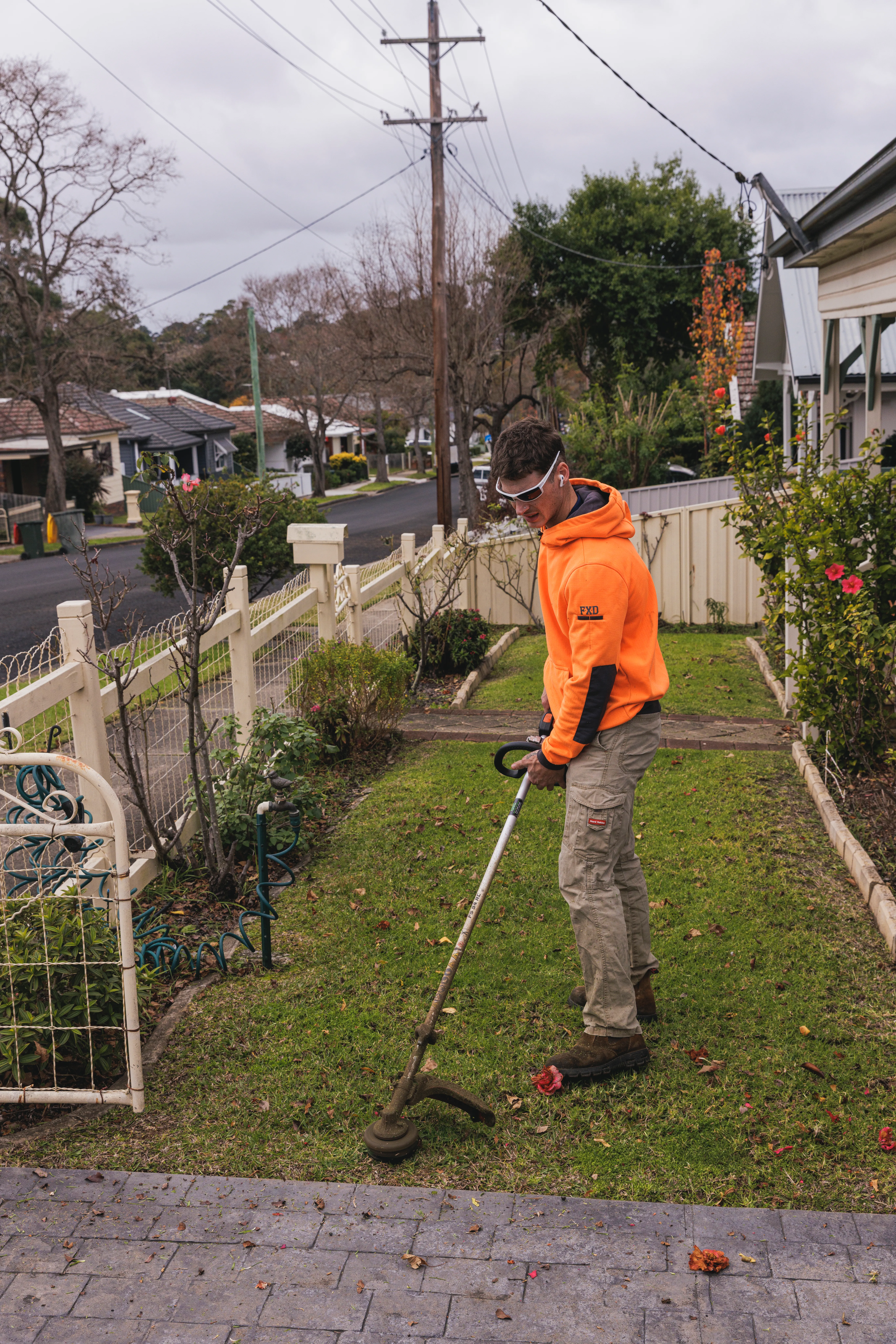 Whipper snipper flat-plane trimming a lawn border in Camden
