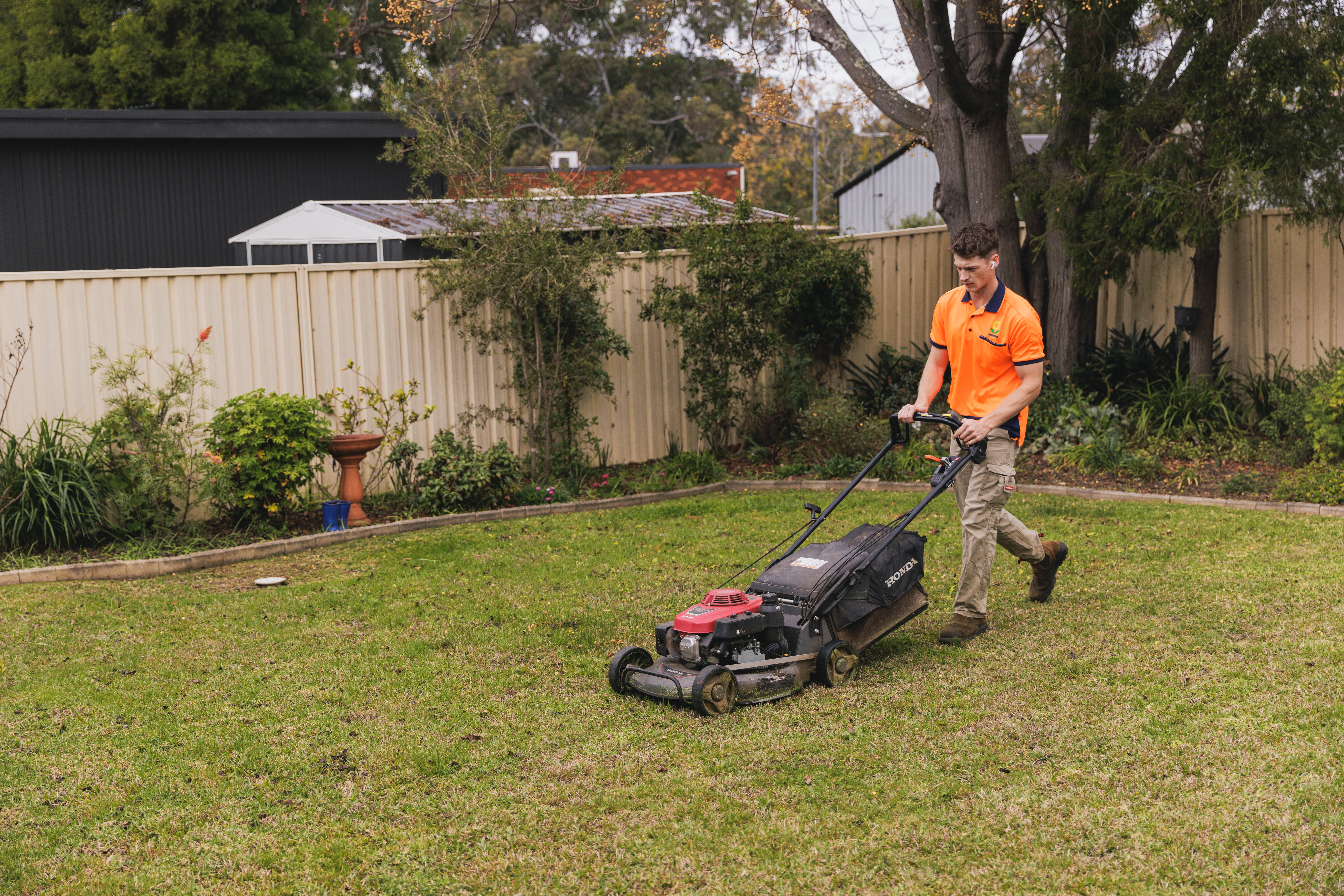 Keeping It Green team member mowing a backyard lawn with a Honda push mower in Camden