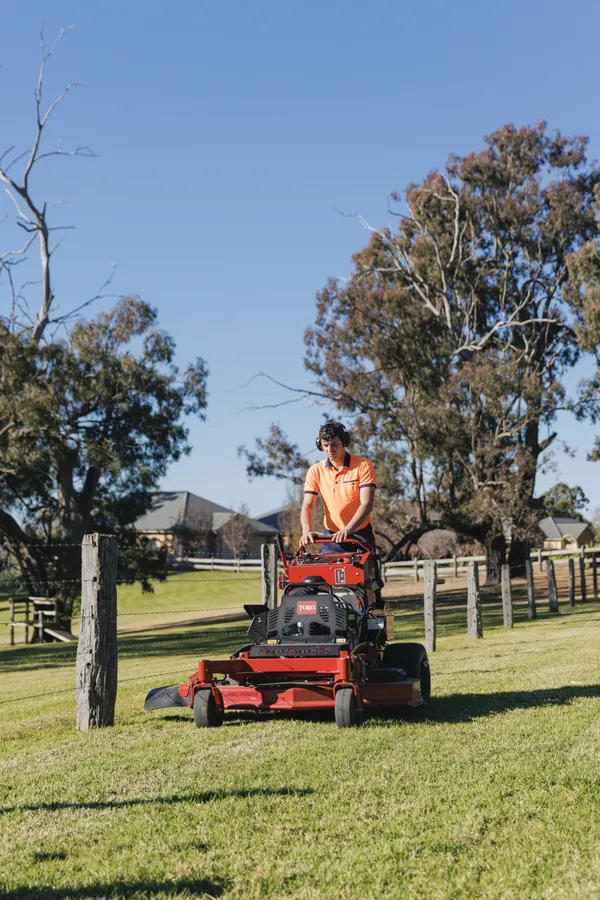 Ride-on mower being unloaded from a trailer for acreage mowing