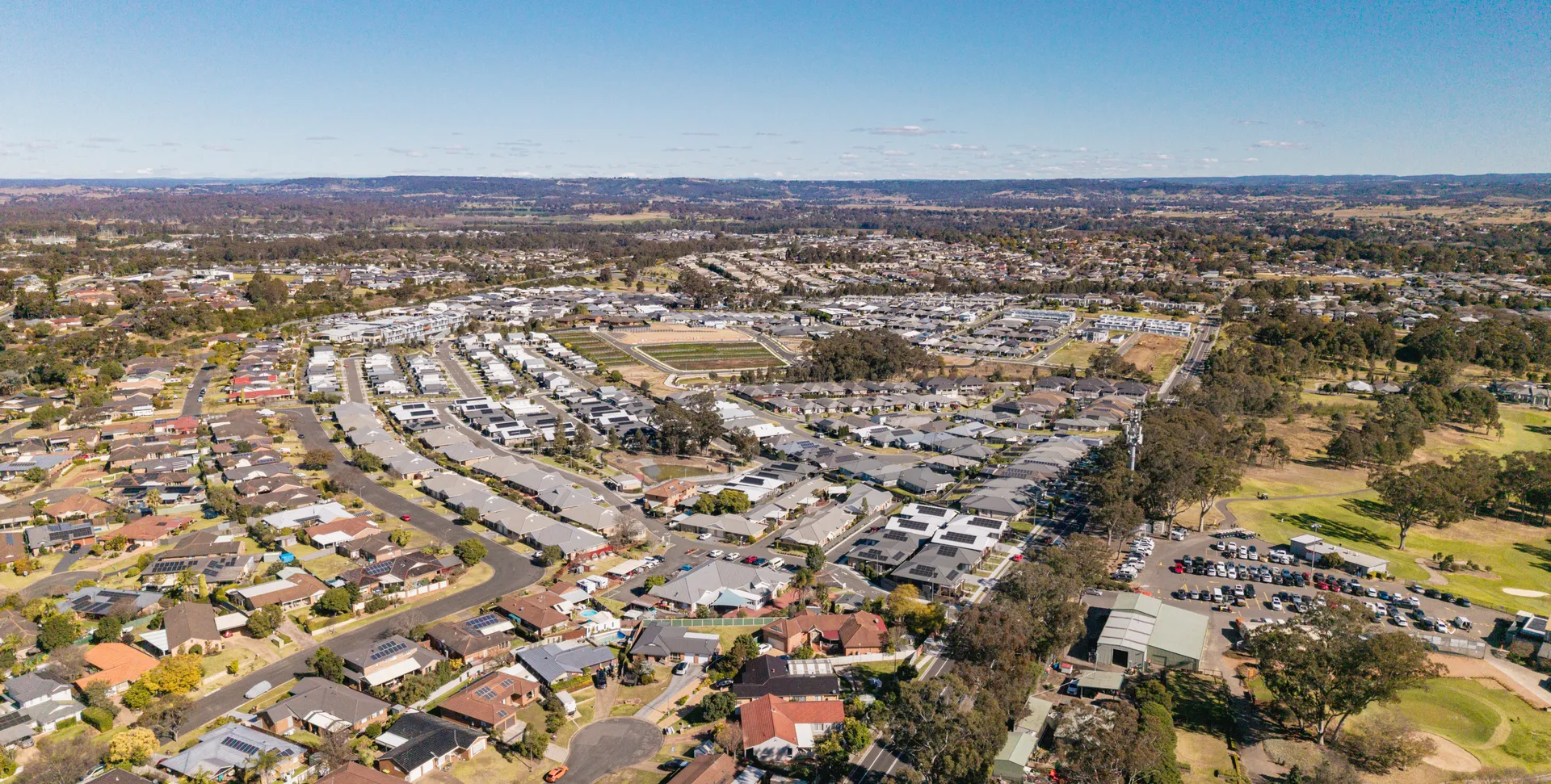Aerial view of Elderslie showing established homes alongside newer estate housing with the golf course beyond