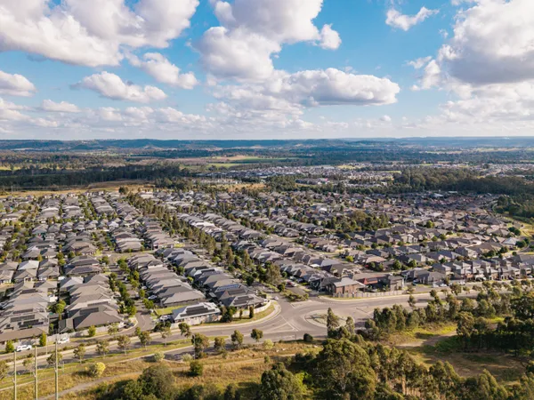 Aerial view of Spring Farm showing new estate homes with farmland and escarpment beyond