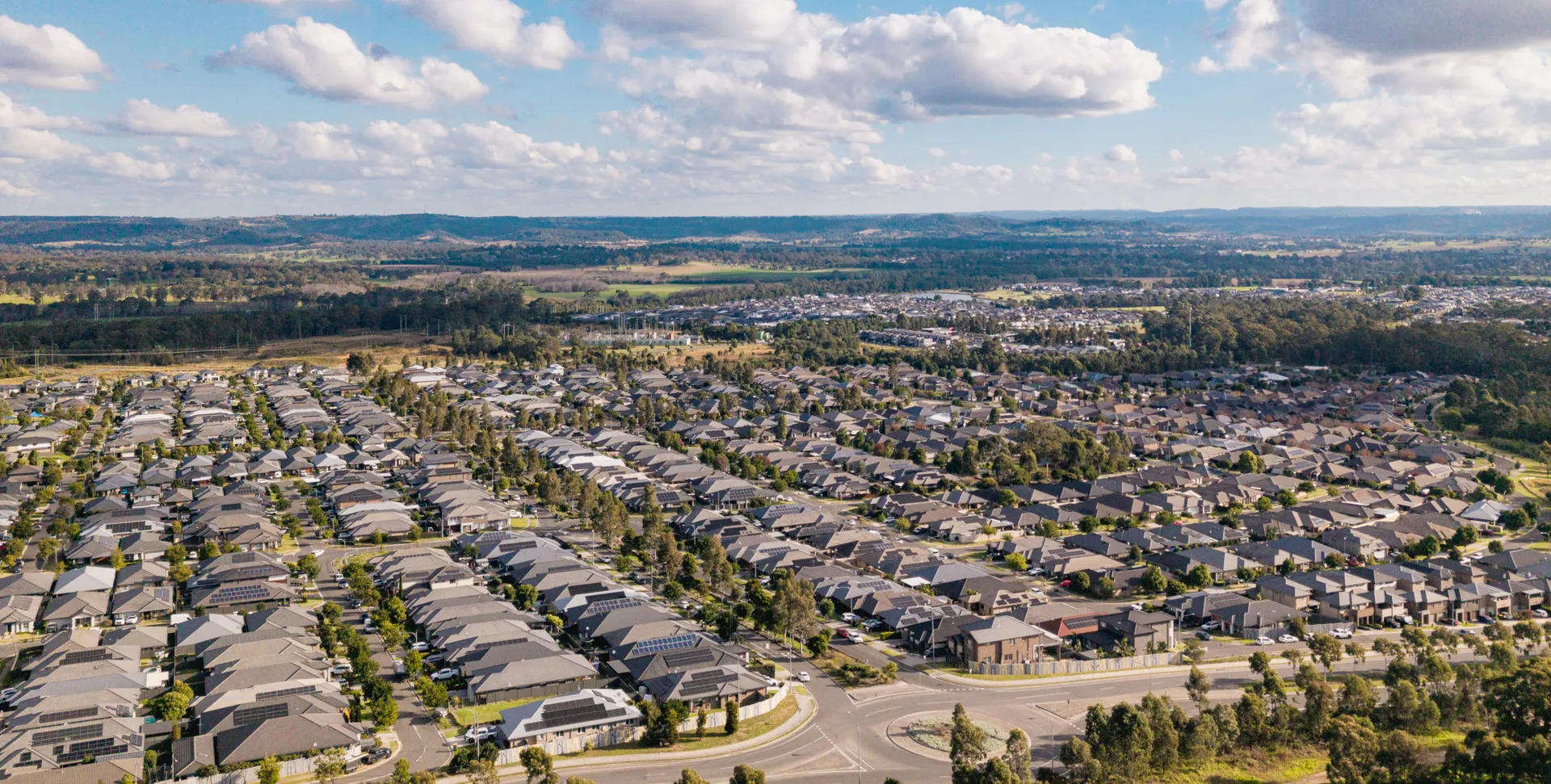 Aerial view of Spring Farm showing new estate homes with farmland and escarpment beyond