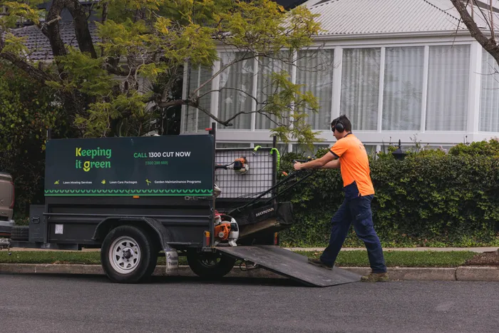 Keeping It Green team member unloading a mower from the branded trailer at a Menangle Park property